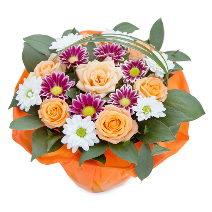 Elevated against a pristine white background, this lush bouquet draws together the best of classic blooms and Clerkenwell's cosmopolitan flair. Rich peach and vibrant orange roses take center stage, their gracefully unfurling petals conveying both elegance and exuberance. Nestled among them, white daisy-like chrysanthemums-with their abundance of slim petals surrounding pale green centers-add delicacy and freshness. Punctuating the mix, deep magenta chrysanthemums present a denser, finely layered burst of colour, ringed around bold yellow-green centers, echoing the creative edge of Clerkenwell's many studios. The arrangement is grounded by dense, dark green glossy foliage-possibly ruscus-which acts as a lush, verdant cushion, supporting and highlighting each bloom. Gently arching above is a single strand of ornamental green grass, bringing movement and a refined, airy structure to the bouquet. All is gathered into a cheerful, crinkled orange cellophane wrap at the base, picking up the warmth of the roses while offering a festive suggestion of ribbon and celebration. Crafted with the expertise found along Clerkenwell Road florists, this floral display speaks of appreciation, warmth, and creativity-perfect as a centerpiece for gatherings or as an inspired gift for someone near City University or the Design District. The image's detailed composition invites close exploration of texture, colour play, and care in arrangement.