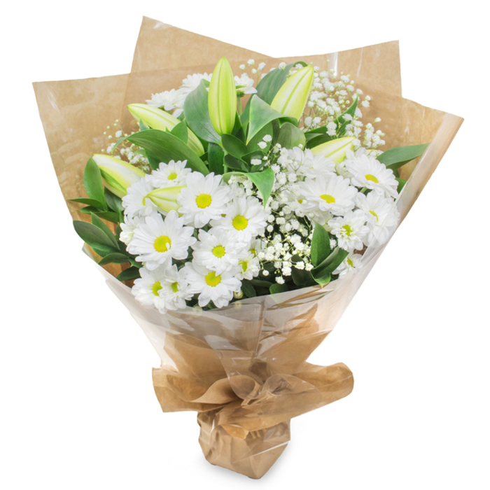 Displayed upright against a spotless white background, this refined bouquet of white and green flowers appears as though it has just been finished on the workbench of a Clerkenwell florist, ready for a thoughtful delivery. The arrangement is dominated by generous clusters of white chrysanthemum heads, daisy-like and intricate, each blossom formed from numerous slim petals that radiate outward in precise layers. At the centre of each bloom, a rounded yellow-green eye glows softly, adding a hint of colour that enlivens the otherwise monochrome palette. Between these fully open flowers, several tall lily buds rise, still closed and quietly sculptural, their elongated forms cloaked in pale green with soft creamy tips that speak of blossoms that will unfold over the coming days. Scattered throughout the bouquet, tiny white gypsophila flowers, commonly known as baby's breath, create a gauzy veil, their delicate clusters resting lightly atop the sturdier blooms. Surrounding everything, a frame of glossy dark green foliage adds structure and depth, the leaves curving gently to cradle the flowers and give the arrangement a natural, garden-fresh feel, reminiscent of a peaceful walk through nearby Exmouth Market or past one of Clerkenwell's hidden courtyards. The stems are bound tightly and encased first in rustic brown kraft paper, which folds into a loose cone and introduces an earthy, textured base, then wrapped again in sheer clear cellophane that offers subtle reflections and protects the fresh petals. Secured neatly at the bottom, the bouquet looks ready to be placed beside a photograph, taken to a remembrance service, or sent as a quiet message of sympathy or recovery, conveying purity, grace, and steady, understated support.