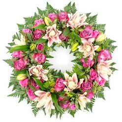 A lush circular wreath of sympathy flowers appears suspended against a pristine white backdrop, its colours and textures glowing as if lit by soft daylight filtering into a Clerkenwell townhouse. At the heart of the design is a generous mix of roses, flowing in a gentle rhythm of deep magenta, vivid fuchsia, and muted blush pink. Some roses are fully blown, with ruffled petals spiralling outward like silk, while others are still tightly furled, capturing the sense of a life remembered through many stages. Interwoven with the roses are elegant double lilies, their wide petals layered in delicate tiers of cream, blush, and pale peach, a few blooms fully open to reveal intricate centres, others held in slim, green buds promising quiet unfolding. Encircling and cradling these blooms is a rich mantle of greenery: soft, feathery fern fronds, glossy broad leaves with subtle variegation, and deep green foliage that echoes the leafy calm of nearby Clerkenwell Green. The greens form a soothing counterpoint to the warm pink palette, giving the wreath both structure and softness. Crafted into a perfect ring, the flowers and foliage symbolise an endless embrace, making this design a comforting choice for funerals, wakes, and remembrance gatherings in local churches or crematoria. The calm white background strips away distraction, allowing the emotional weight of the wreath to come forward: a loving, dignified tribute created by skilled hands, quietly expressing sympathy, gratitude, and the enduring connection between the departed and those who remain.