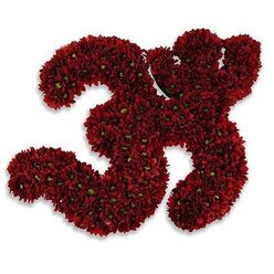 A reverent, handcrafted floral tribute shaped into the sacred Om symbol, composed entirely of deep red chrysanthemum blooms whose dense packing creates a rich, velvety tapestry of colour and meaning. Each chrysanthemum is arranged with careful intention: the petals lie compact and soft, catching a subdued studio light that brings out garnet and wine tones across the curves of the symbol. Tiny green centres peek through in places like steadying breath-small, bright anchors within the dark petals-offering a subtle visual heartbeat to the whole piece. The white background strips away distraction, heightening the symbol's presence and allowing the eye to follow the graceful swirls as one might trace a mantra with a fingertip. There is a faint, comforting aroma of fresh chrysanthemums, an earthy sweetness that steadies the senses and deepens the piece's role as an offering, a visual prayer for solace. The arrangement's craftsmanship balances strict form with organic softness: the chiseled outline of the Om is precise, yet the individual blooms retain their natural movement, lending warmth and humility. Seen through the lens of a Clerkenwell florist familiar with St John's atmosphere and quiet churchyard vigils, this creation reads as a vessel of comfort - appropriate for memorials, moments of private mourning, or spiritual gatherings - holding space with gentle dignity rather than theatrical flourish. The shadowed lift beneath the composition gives it subtle depth, as if the symbol hovers slightly above the page, holding a small, steady light.