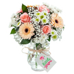 This glowing bouquet channels the fresh, creative spirit of Clerkenwell, artfully gathered and arranged in a clear glass vase that rests against a pure white background. At the heart, pale peach-pink roses, blooming with soft layers, radiate classic sentiment, echoed by friendly gerbera daisies in gentle apricot and tangerine tones. The arrangement feels full and balanced, with clusters of snowy white chrysanthemums nestled among the larger blooms, some revealing tender green centers that bounce with life. Wisps of baby's breath create a sense of gentle volume, airy as the mornings overlooking Charterhouse Square. Deep green leaves, reminiscent of leafy city corners, peek through to provide natural depth and accentuate the freshness of each flower. The bouquet is bound at the neck of the vase with rustic twine, tied in a thoughtful bow, from which hangs a small, pristine gift tag waiting to bear a personalized message. Through the clear, subtly curved glass, stems and water are visible-a detail that grounds the arrangement in authenticity and freshness. The overall impression is warmth, care, and the unique vibrancy that comes from locally crafted floristry. Perfect for an anniversary, to say thank you, or simply to bring a flourish of colour to a home or office, this bouquet captures both artistry and the friendly community spirit found in historic Clerkenwell.