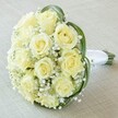 A close-up, high-angle perspective reveals a bouquet assembled with the precision and heart characteristic of Clerkenwell's finest florists. At its center, a harmonious cluster of a dozen or more creamy yellow roses-petals softly unfurling and catching the ambient light-sits surrounded by a frothy layer of baby's breath. The white Gypsophila lends a dreamlike, ethereal softness, enhancing the radiant tones of the roses and bringing to mind early mornings along the Amwell Street gardens. Bold, looping arcs of deep green foliage provide a vivid framework, their modern curves adding visual intrigue and echoing the contemporary design energy found in Clerkenwell's art studios. The bouquet's stems are gathered together, expertly wrapped in a pristine white satin ribbon, forming a classic handle that's both practical and elegant. The gentle background-a neutral cream fabric-subtly recedes, ensuring every detail of the floristry commands attention. Designed for significant moments-a bride's first step down the aisle at a local venue or a heartfelt anniversary gesture-this bouquet radiates purity, sophistication, and a timeless romance. Every choice reflects the same-day freshness and artistic vision available through Clerkenwell's leading floral designers, making it perfect for celebrations or thoughtful commentary on wedding and floral aesthetics.