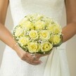 Within the vibrant lanes of Clerkenwell, this bridal bouquet is lovingly captured as a radiant sphere of happiness, gently enfolded by the bride's hands just above the historic pavements. The arrangement blooms with creamy yellow roses, each petal curled in a soft embrace, their gentle glow heightened by the lace-suggestive gown in the background. Misty tufts of baby's breath entwine throughout, adding a cloudlike softness and evoking the dreamlike calm of early Spring in local London squares. Wrapped discreetly at the base are slender threads of dark green, reminiscent of the neighbourhood's cherished artisanal detail and creative edge. The bride's manicured fingers, subtle in pale pink, showcase a single ring, reflecting her devotion and readiness for the future. The bouquet's subtle fragrance-implied visually-speaks of new beginnings and romance, a perfect companion for ceremonies near Exmouth Market or intimate celebrations close to Spa Fields. The entire scene embodies the spirit of Clerkenwell Flowers: a harmonious blend of tradition and modern romance, promising joy and floral beauty for every special moment.