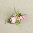 Expertly crafted by local Clerkenwell florists, this boutonniere rests gracefully on a lightly woven, creamy beige linen-a canvas that highlights every nuanced detail. At its centre blooms a soft, pastel pink rose, its petals tenderly curled inwards, epitomising freshness and quiet beauty. Companioned by a blush-pink alstroemeria with gently ruffled petals and a heart touched with yellow and delicate markings, the core of the design feels both classic and modern. Wispy clusters of baby's breath punctuate the composition, while lively spheres of green mini mums peek from among lush foliage, reminiscent of the verdant pocket gardens along Clerkenwell Road. Slender, dark greenery arcs upwards, balanced by broader, folded leaves that cradle the base and supply natural structure. Encircling the stems is a vibrant fuchsia pink satin ribbon, tied in a compact, celebratory bow-its glossy finish lending a festive accent that catches the light. Illuminated by soft, ambient daylight, this floral accessory radiates romance and sophistication-perfect for brides, groomsmen, or anyone marking a special occasion in the heart of Clerkenwell. Every carefully chosen bloom and blade tells a story of local expertise, artistry, and the joy that flowers bring to life's finest events.