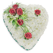 A tender, heart-shaped memorial crafted from a dense cushion of pristine white chrysanthemums sits against a clean white backdrop, the petals forming a soft, cloud-like surface that suggests quiet and purity. Five deep crimson roses punctuate the white field: a small cluster of three rests on the upper left, their velvety petals open and soaked with the gentle, sweet scent of roses, while two single blooms sit thoughtfully near the upper right curve and the lower point of the heart. Each solitary rose is cradled by a few glossy green leaves and slender, arching blades of bear grass, introducing a subtle, flowing movement across the composition. The clustered roses are nestled into a restful mix of glossy ruscus, delicate fern fronds and tiny white filler blossoms that lift texture without distracting from the central silhouette. A narrow emerald-green satin ribbon traces the entire edge of the heart, its sheen providing a tidy frame that reads as both solemn and refined beneath soft overhead lighting that reveals the chrysanthemums' layered depth. The arrangement conveys a quiet choreography of colour-pure white washed with points of deep red and cool green-that speaks of remembrance, respect and enduring love. As a local florist who often prepares tributes for services at nearby Bunhill Fields or St John's Church, I picture this piece laid with care at a chapel or delivered to a family home in Clerkenwell. The composition is designed to cradle memory and scent, offering a gentle, dignified farewell that reads clearly in photographs, print and in-room settings alike.