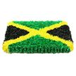 The photograph captures a bold, rectangular floral tribute designed in the unmistakable colours and layout of the Jamaican flag, carefully arranged for a funeral or memorial. The piece appears thick and cushion-like, with tightly packed flowers forming a plush, almost velour surface that rises slightly from the background. A strong golden-yellow X-shape dominates the design, the diagonal bands created from small, ruffled blooms whose petals overlap to give a soft, sunlit effect. This striking saltire divides the tribute into four precise triangles: top and bottom filled with vivid, grassy green flowers that recall the vibrant planting in London's inner-city gardens and hidden corners near Clerkenwell Green, and left and right composed of deep, matte black petals that add solemn contrast and depth. The colours meet in clean, sharp lines, reflecting careful craftsmanship and an eye for symmetry. The tribute is photographed on a pure white surface with even, gentle lighting that highlights every texture and tiny shadow within the petals, making the design feel rich and three-dimensional. Emotionally, it conveys both pride and peace, a way of honouring Jamaican identity within a farewell ceremony, whether in a local Clerkenwell church or a quiet crematorium chapel. The handcrafted nature of the piece hints at patient, loving work by a local florist, turning fresh stems into a meaningful symbol of homeland, family stories, and the bonds that connect communities across generations.