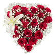 A lush, heart-shaped floral composition sits centered against a pure white backdrop, its silhouette confidently defined by dozens of deep crimson roses. Each rose bears velvety petals in varying stages of bloom - from tightly furled buds to broad, open cups - their rich, dark red catching subtle highlights and casting soft shadows that add depth to the heart. Light, cloud-like sprays of tiny white baby's breath (Gypsophila) weave through the roses and outline the edge of the heart, their feathery clusters softening the boldness of the red and creating an airy halo that seems to lift the design. Nestled in the upper-left curve, an immaculate white lily unfurls its broad, waxy petals; near its center a faint wash of creamy yellow leads the eye to the warm yellow-orange stamens that punctuate the blossom. The juxtaposition of the lily's smooth, sculptural form against the dense, velveteen roses creates a pleasing tension between strength and delicacy. If you imagine scent, the image suggests a heady, classic perfume - warm damask rose with a clean, verdant lift from the gypsophila and a bright, green note from the lily. The clean white background isolates the arrangement, encouraging focus on texture, form, and mood rather than setting. A bouquet like this reads as a crafted declaration of love and devotion, suitable for anniversaries, proposals, or a heartfelt tribute; it speaks with an intimacy that feels at home in Clerkenwell's quieter corners, perhaps brought by hand from a shop near Exmouth Market or delivered to a flat overlooking St John's Square.