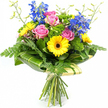 This image shows a lively hand-tied bouquet displayed against a clean, white background, every detail illuminated as if under soft studio light. At the centre sit several pink roses in various stages of opening, their velvety petals curling outward with a gentle, romantic ease, conjuring the feeling of a thoughtful surprise arriving at a Clerkenwell doorstep. Around these, bright yellow gerbera daisies with dark, espresso-coloured centres provide a joyful counterpoint, their layered petals forming crisp, circular blooms that radiate warmth and positivity. Rising elegantly above, tall stems of saturated blue delphinium carry cascades of small florets, adding height and a cool, sophisticated note that balances the bouquet's sunny yellows and tender pinks.
The arrangement is richly framed by layers of greenery. Soft, feathery fern fronds peek out from the sides and lower edges, lending movement and a slightly whimsical, garden-picked feel, akin to greenery seen in nearby parks and churchyards around Clerkenwell. Tucked throughout are rounded tufts of bright green filler flowers, their fine textures creating a plush, almost moss-like effect that fills any gaps and enhances the sense of abundance. At the base of the flower heads, broad, glossy leaves-some showing gentle stripes of lighter green-are expertly curved to form a structured collar, giving the bouquet a polished, contemporary silhouette. Slender, upright stems topped with tiny buds emerge lightly from the top, suggesting ongoing growth and freshness. Below this collar, the long green stems gather neatly, wrapped in a soft cream or pale green material and tied with a simple bow. The overall design, as if just prepared by Clerkenwell Flowers for same-day delivery, communicates joy, appreciation, and a bright yet refined elegance suitable for birthdays, thank-you gestures, or everyday celebration.